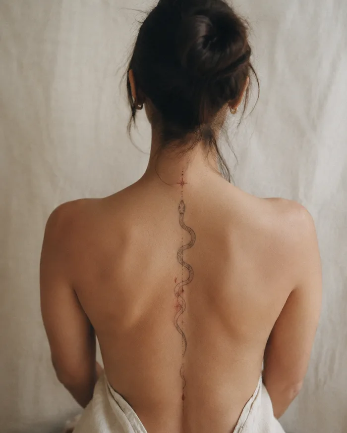 Fine line snake tattoo along a spine